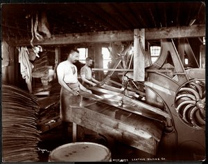 Vue intérieure de deux hommes travaillant avec du cuir et des équipements lourds à la New York Leather Belting Co., New York, 1905